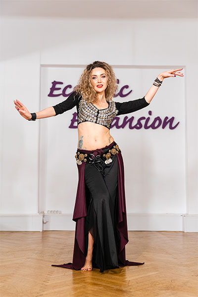 a woman dressed in a belly dance costume dances with her arms